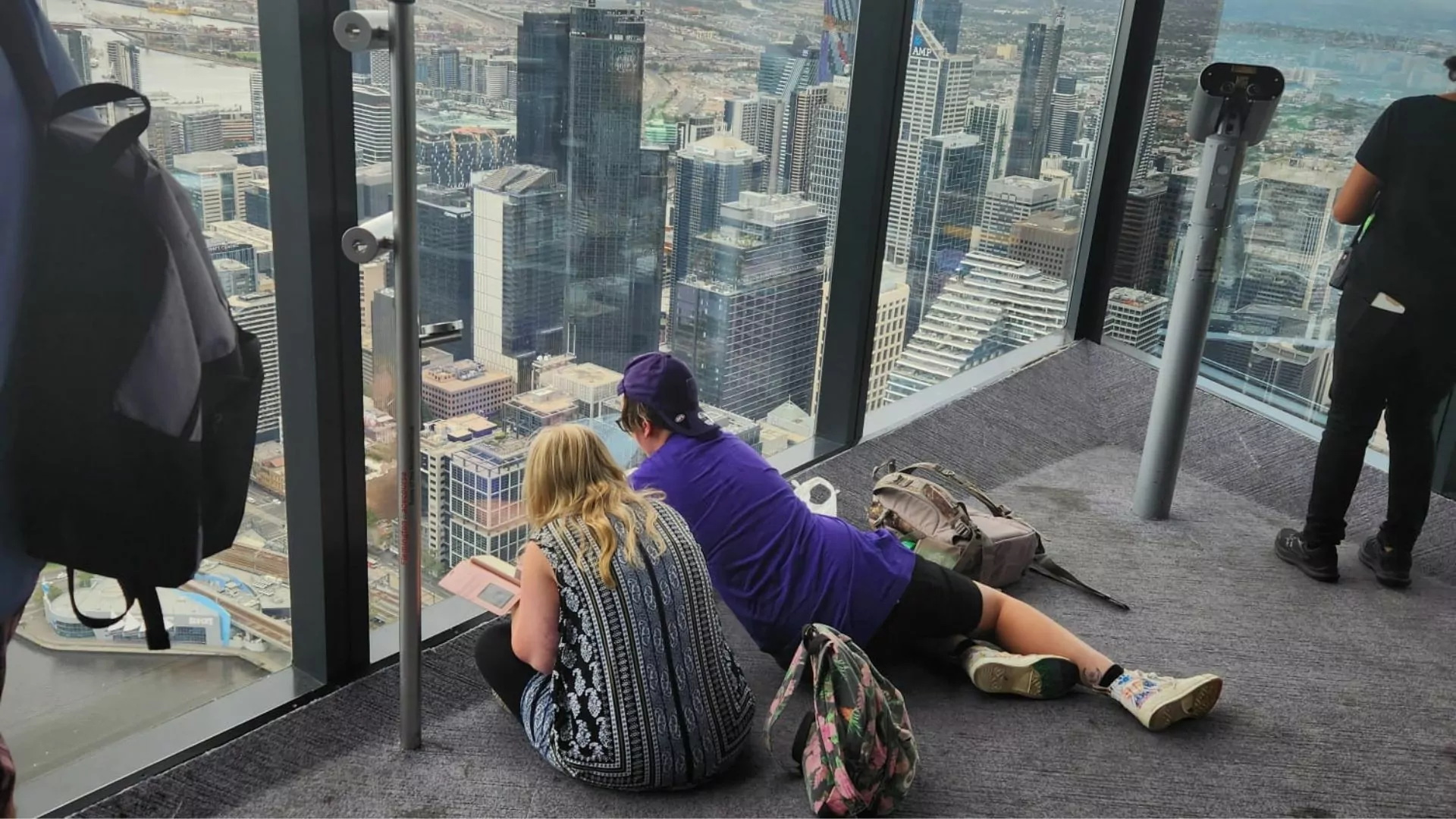 Participant and Volunteer staring out of a high-rise building window onto the city below.
